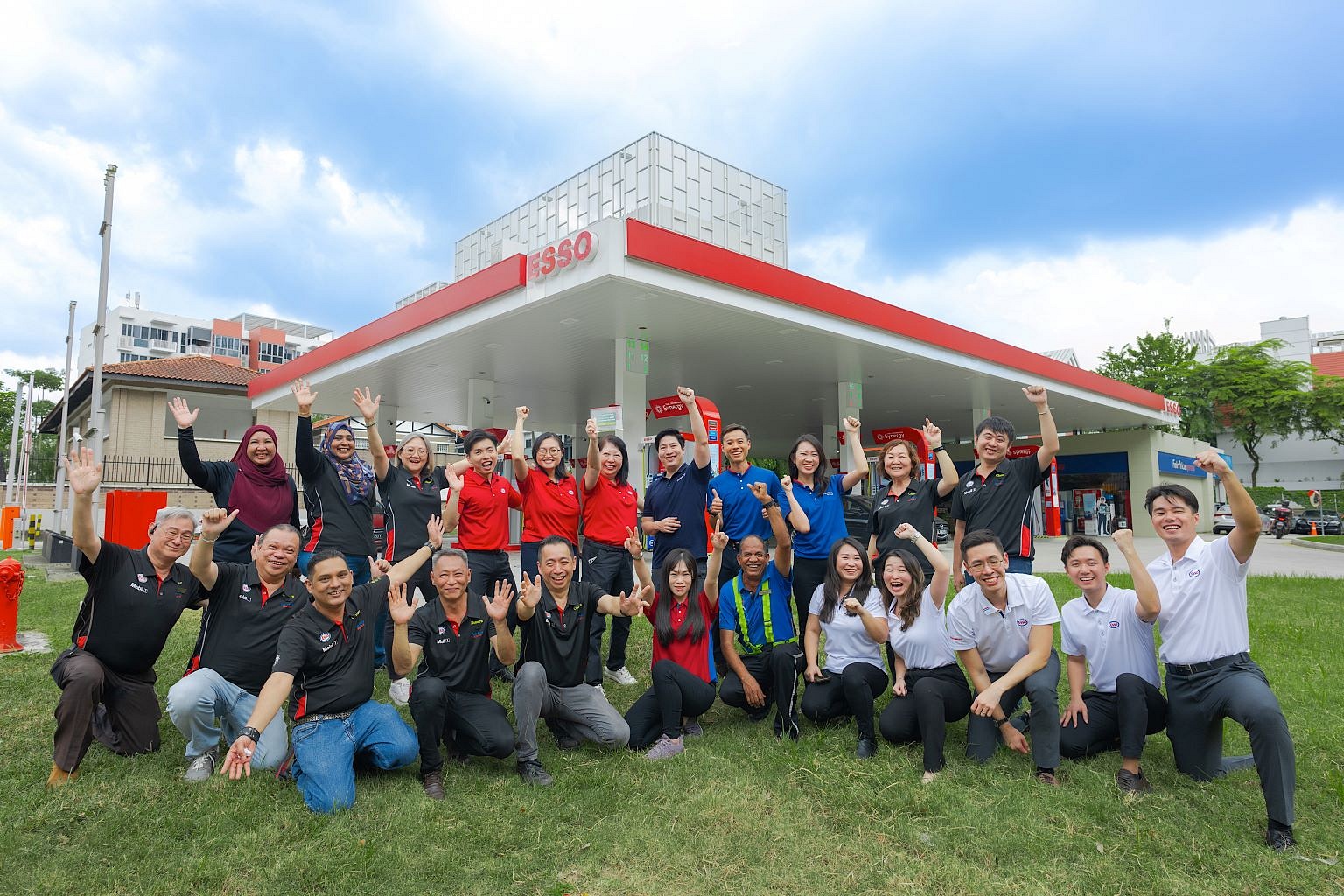 Esso employees standing in front of an Esso station cheering